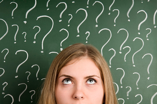 A young woman stares up at question marks drawn on a chalkboard asking herself four questions that may help her determine whether self-directed investing is right for her.