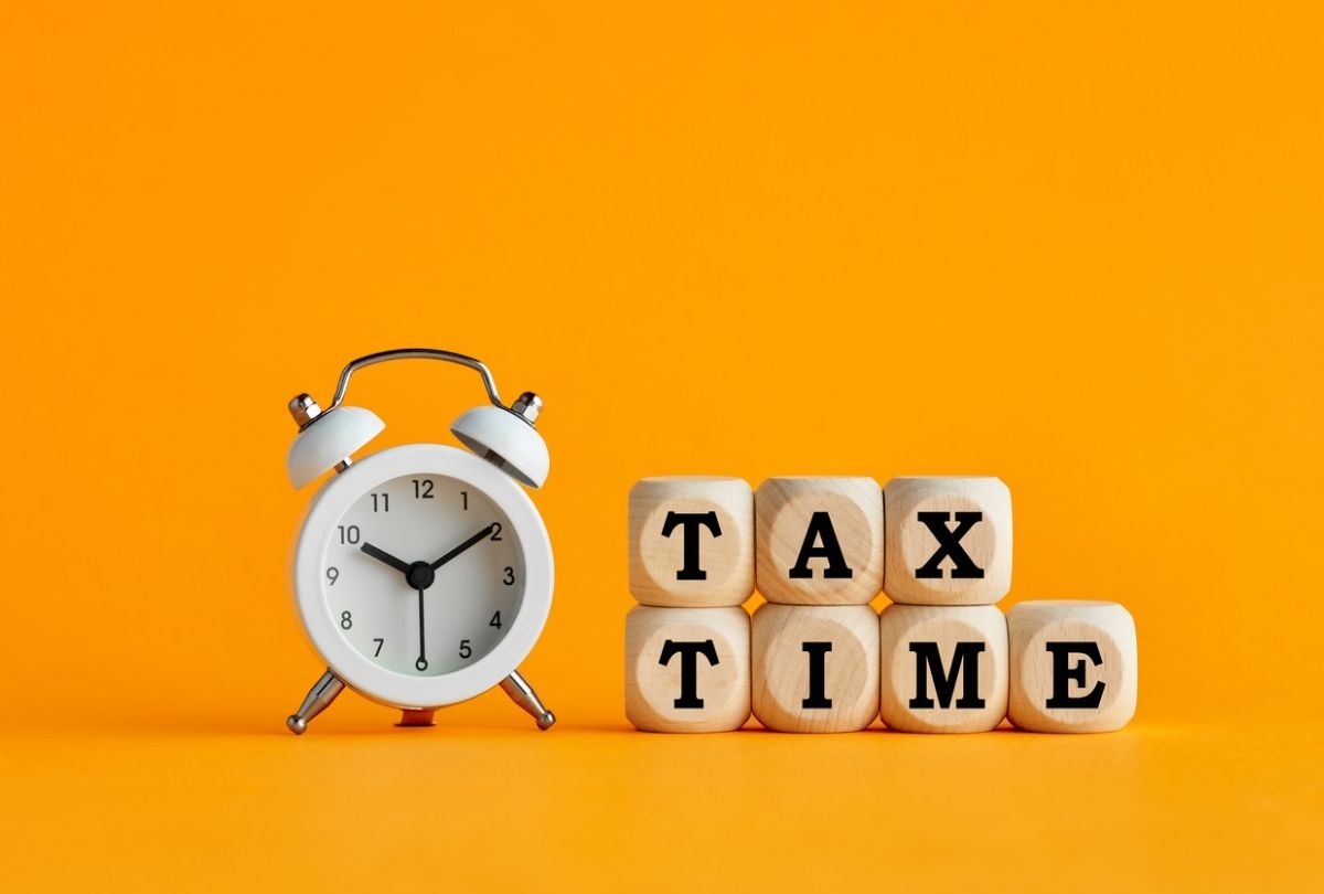 This image of a clock next to letter blocks that spell out tax time represents the upcoming 2022 deadline to file your 2021 income tax return in Canada.