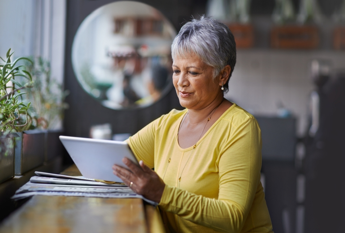 An older woman with an iPad reading the latest CSA report featuring key securities regulators' investor education initiatives.