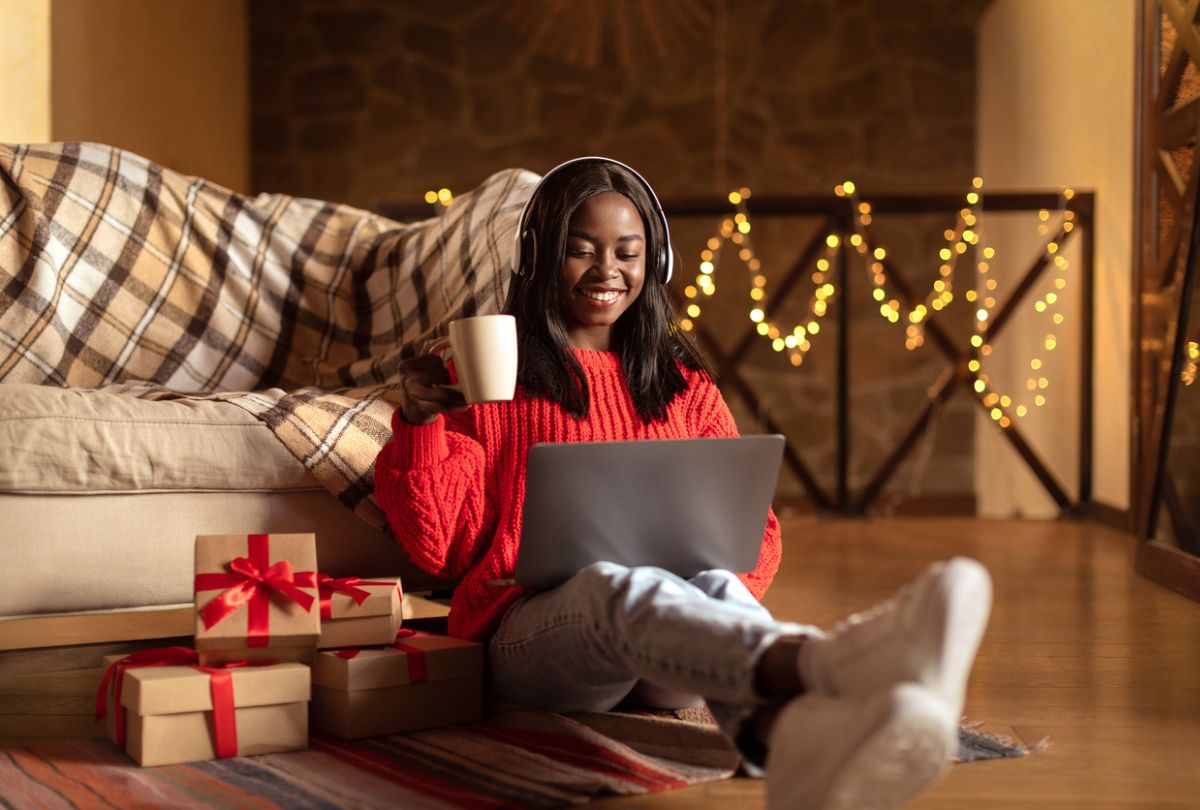 A young woman sits on the floor with a cup of hot chocolate and reviews her new year goals