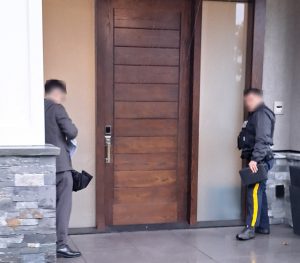 A BCSC investigator and an RCMP officer trying to deliver a warning letter to a suspected money mule.